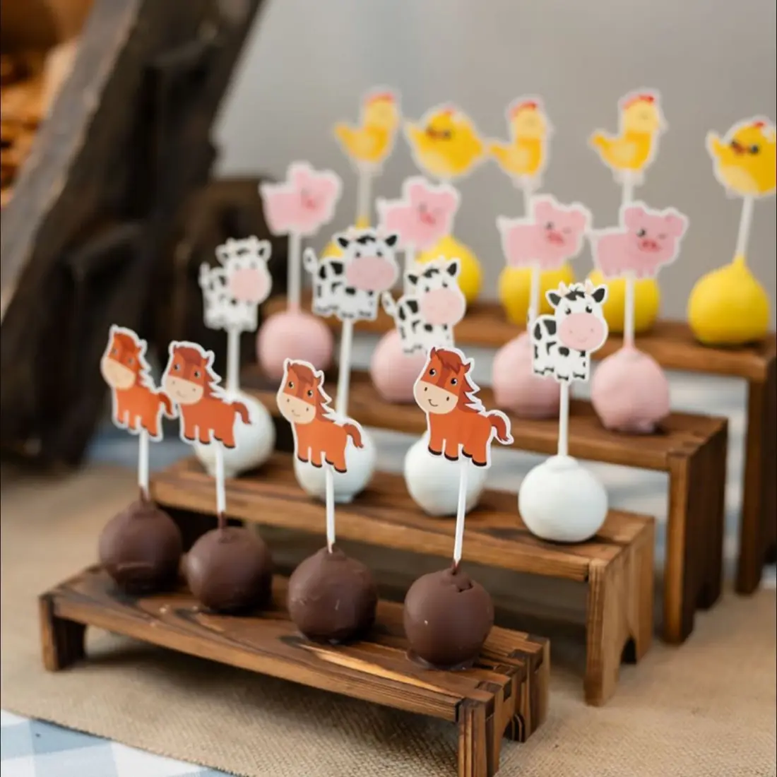 Farm animal cake pops displayed on a wooden stand