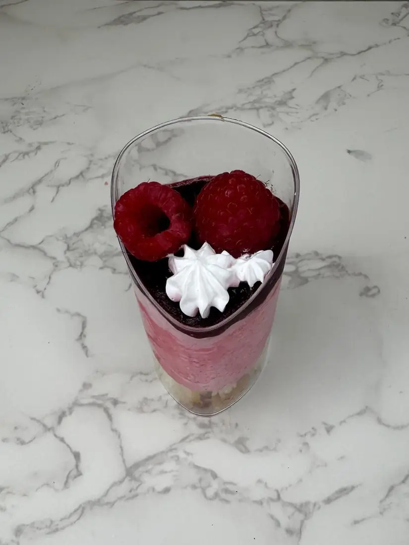 Individual berry mousse cup topped with raspberries and cream