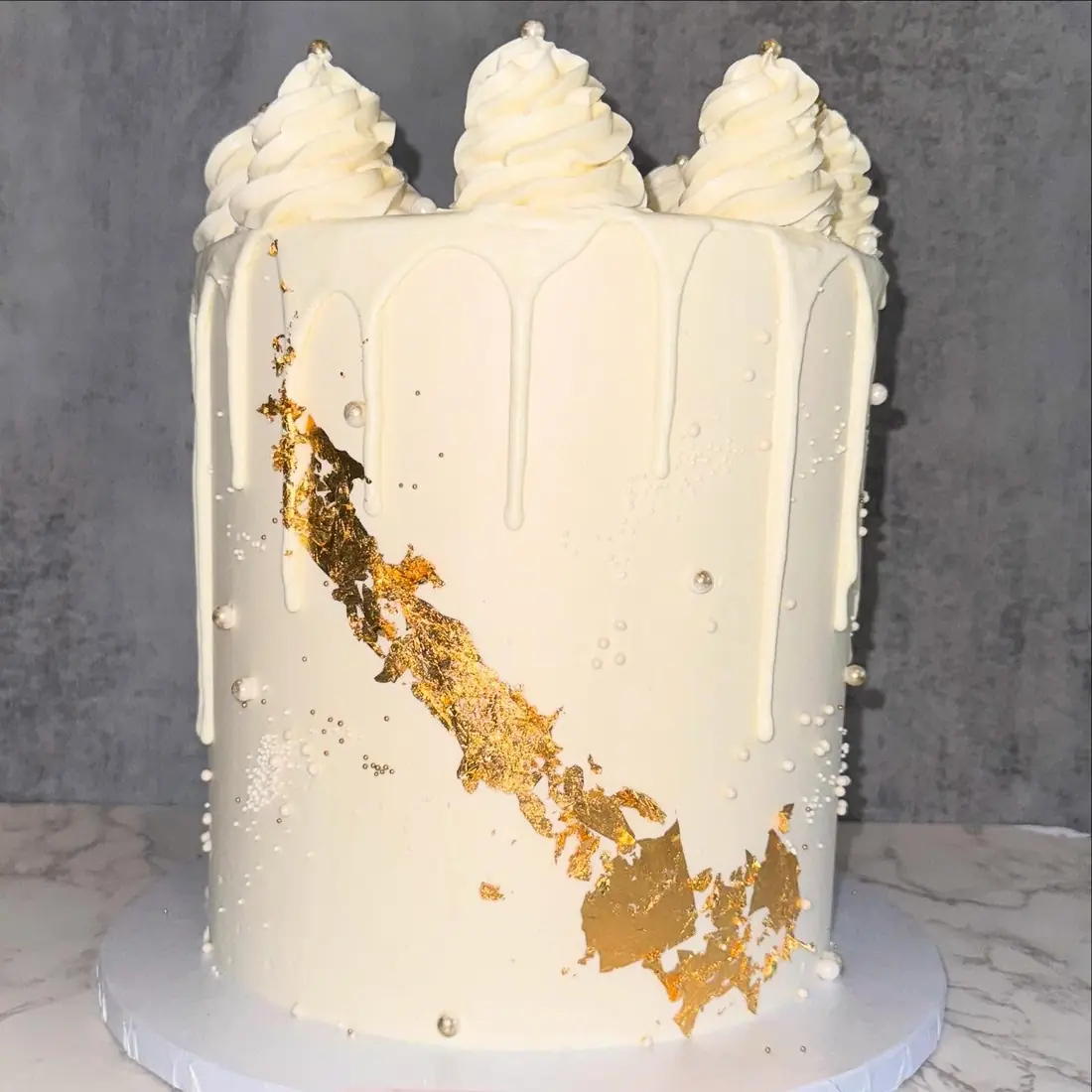 White celebration cake with gold leaf detail by Cakes by Din