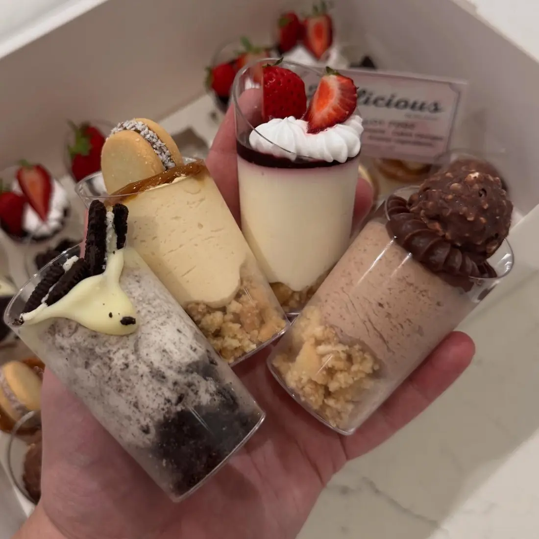Hand holding four layered dessert cups