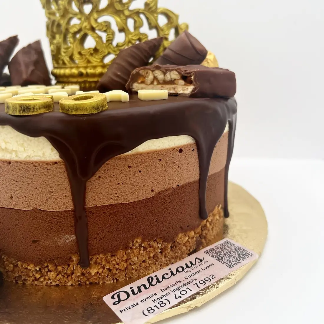 Triple chocolate mousse cake with chocolate drip and gold crown topper