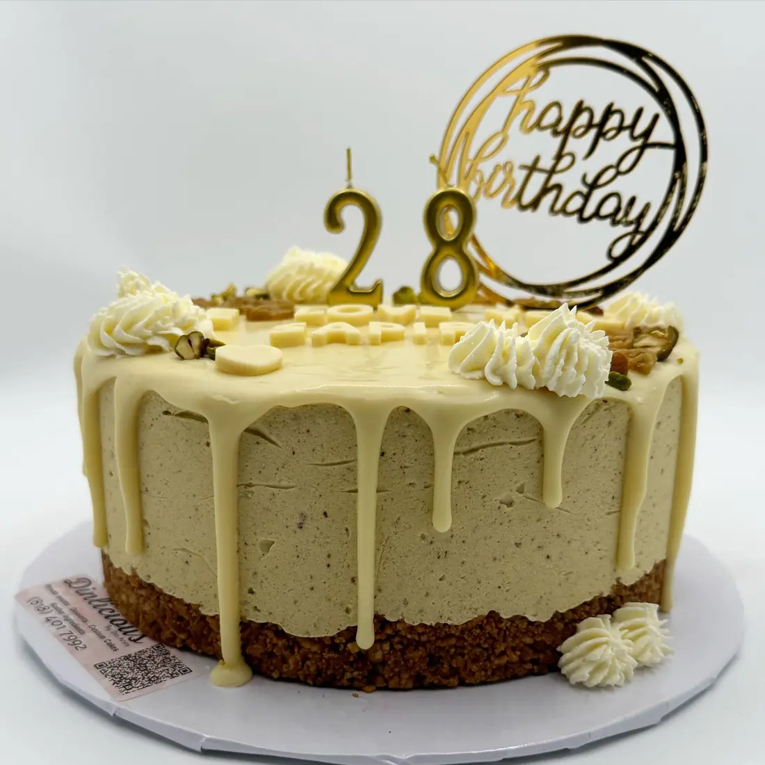 White chocolate pistachio mousse cake with gold drip and birthday topper